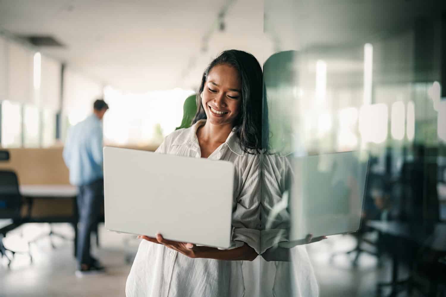 A woman smiles as she holds a laptop. Her cloud infrastructure for business expansion is set up.