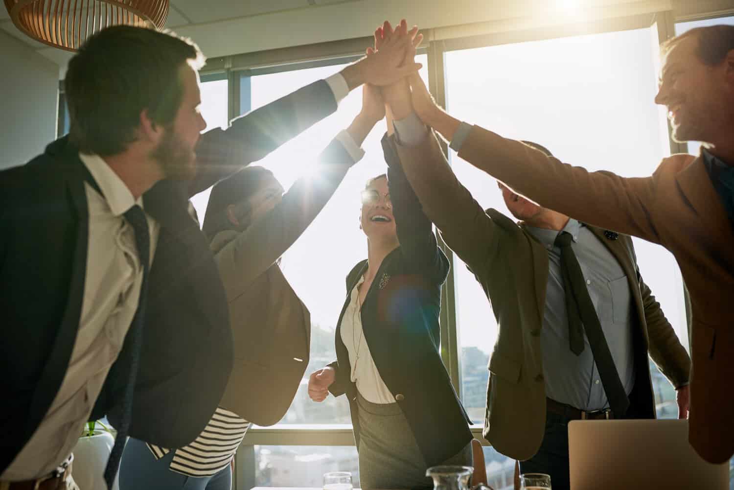 A business team high-fiving after deciding on AWS cloud infrastructure.